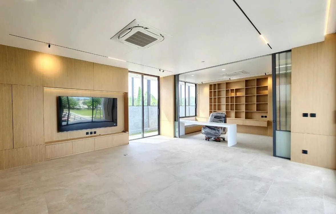 Newly fitted room on site, with oak wall panelling, a recessed TV wall and built-in shelving, the office chair still wrapped in plastic