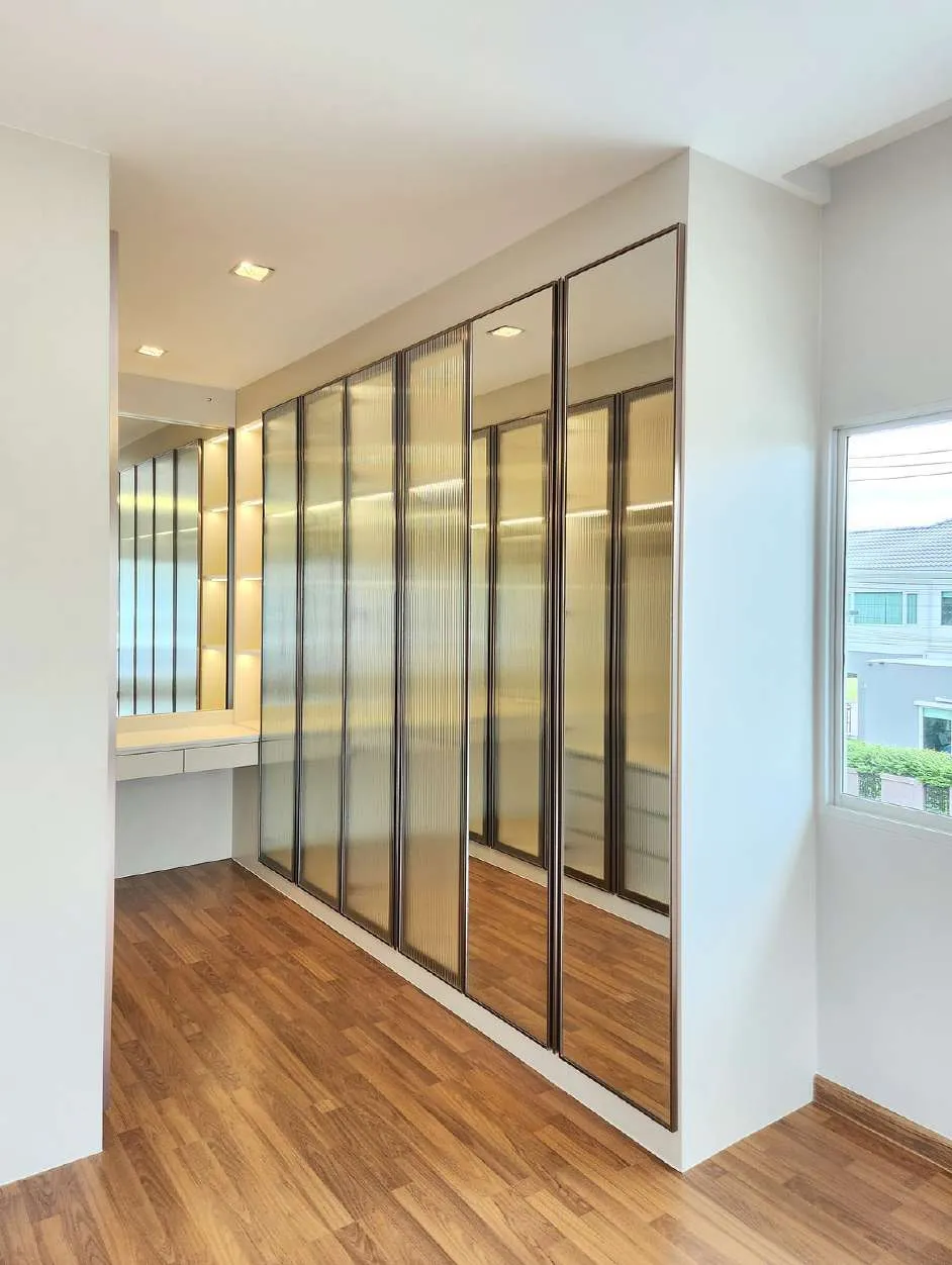 Built-in wardrobe wall with fluted glass doors and a timber floor, finished by OUT