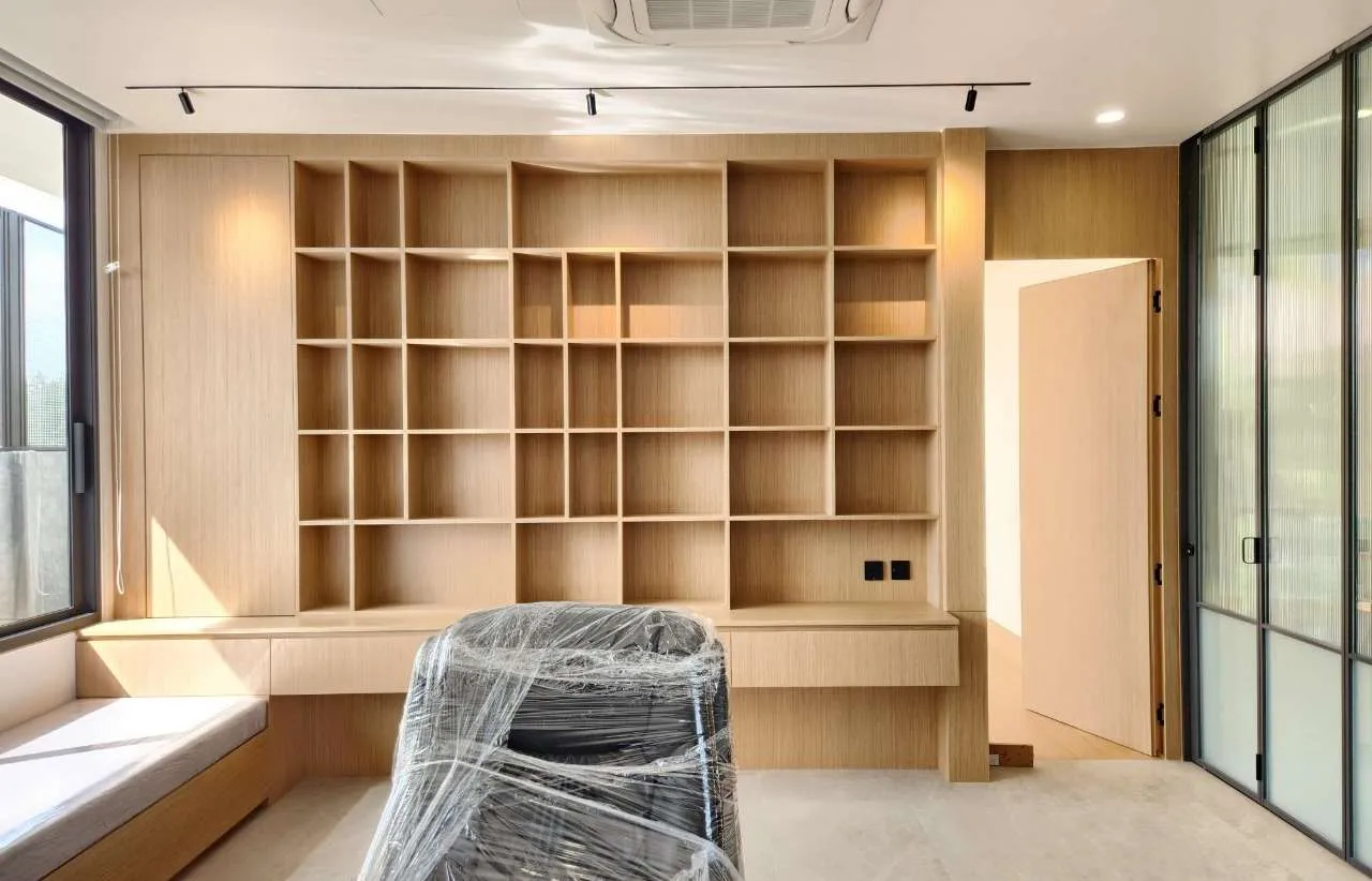 Newly built study with full-height timber shelving and a chair still wrapped in protective film