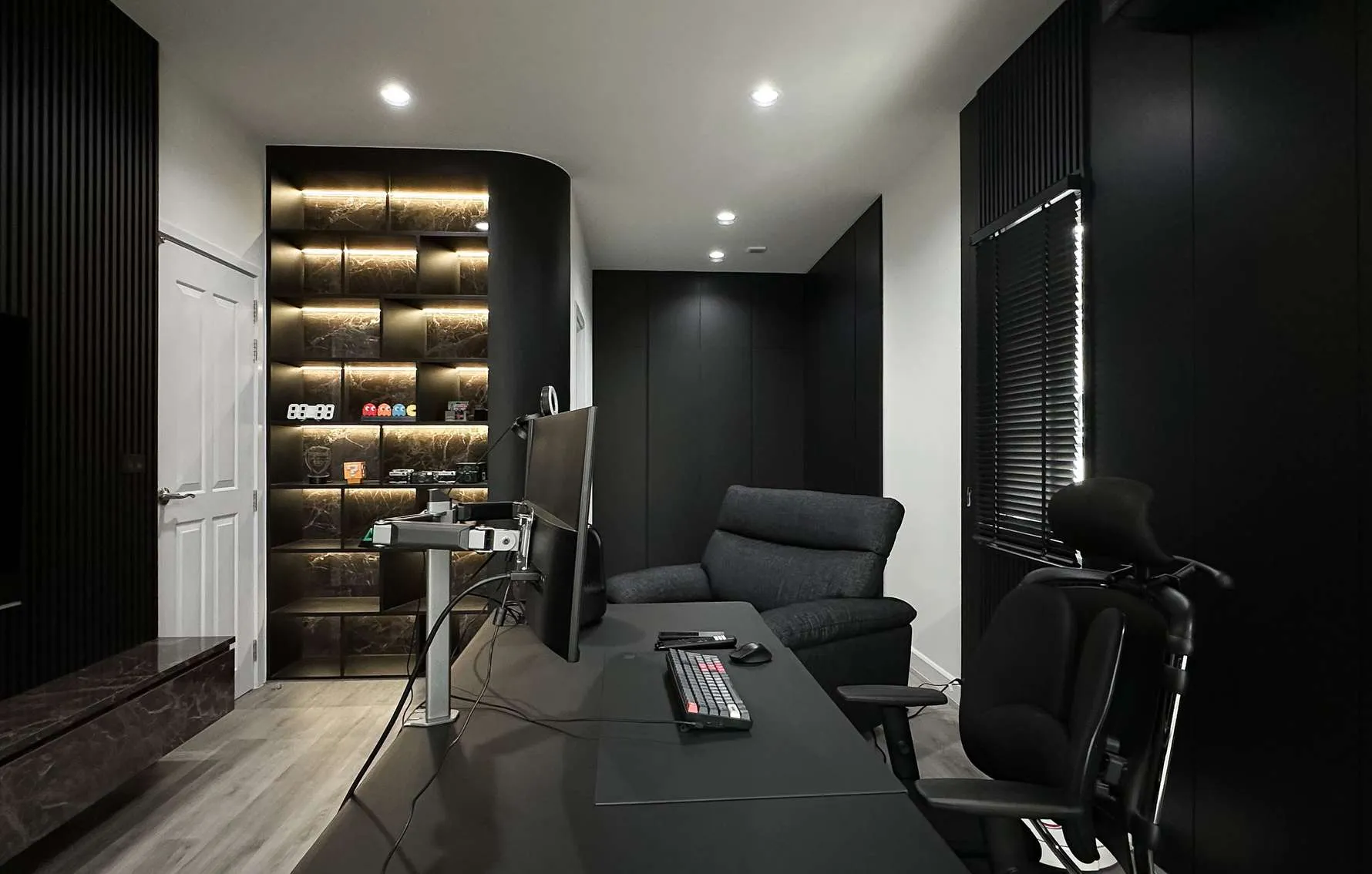 Home office built by OUT at Grandio Rama 3: curved black shelving with lit shelves, flush full-height cabinets and slatted wall panels