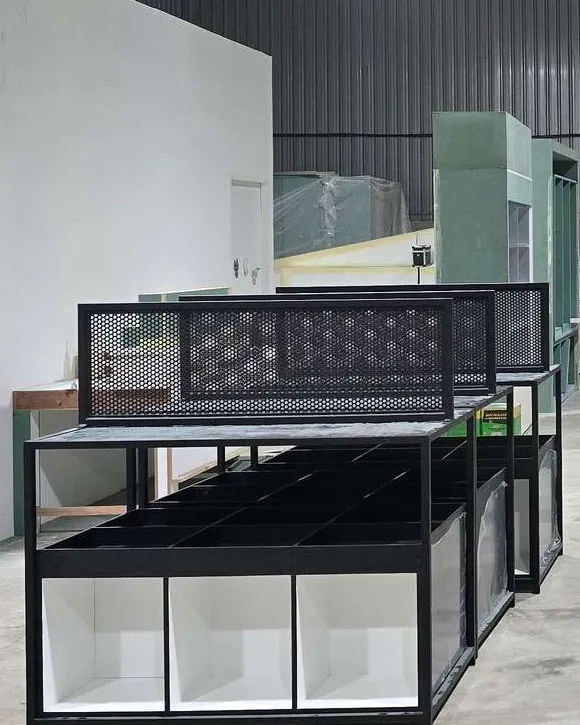 Pre-assembled black steel shelving frames with perforated panels and white open compartments in the OUT workshop